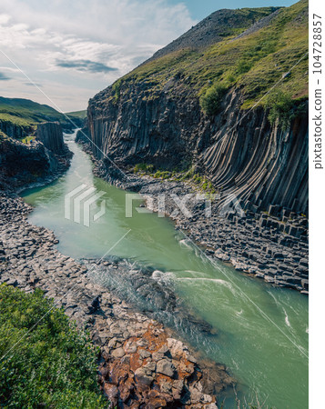 Panorama of Studlagil canyon with basalt pillars and hexagonal rock formations in Iceland Panorama of Studlagil canyon with basalt pillars and hexagonal rock formations in Iceland 104728857