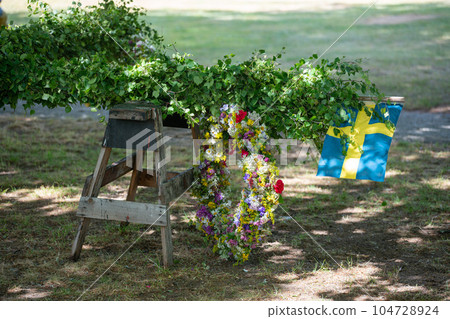 Traditional midsummer pole with Swedish flag awaits the rising ceremony. 104728924