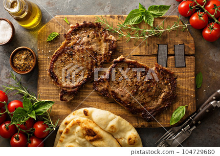 Grilled ribeye steaks on a wooden board 104729680