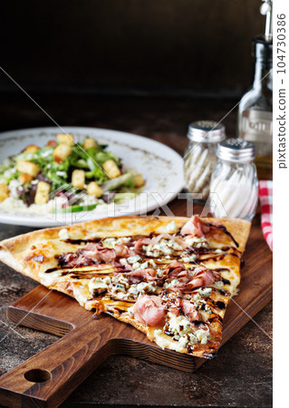 Big slice of pizza with prosciutto, blue cheese 104730386
