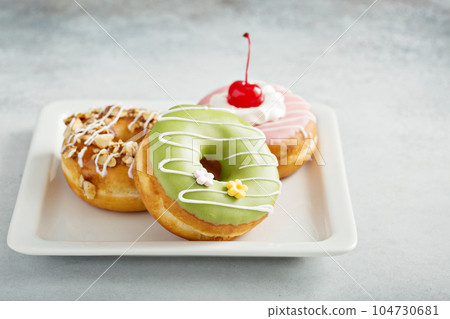 Assorted glazed fried donuts on a plate Assorted glazed fried donuts on a plate 104730681