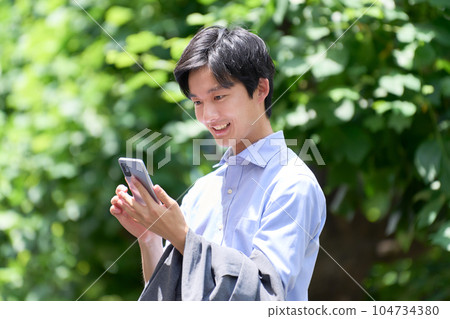一個很高興在戶外看到智能手機的年輕人 一個很高興在戶外看到智能手機的年輕人 104734380