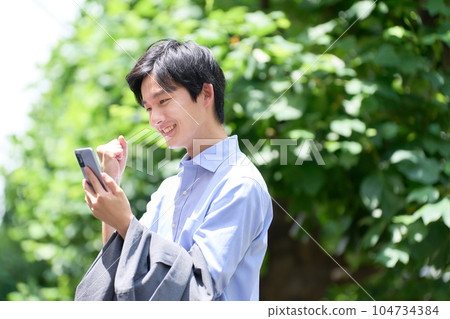 一個很高興在戶外看到智能手機屏幕的年輕人 一個很高興在戶外看到智能手機屏幕的年輕人 104734384
