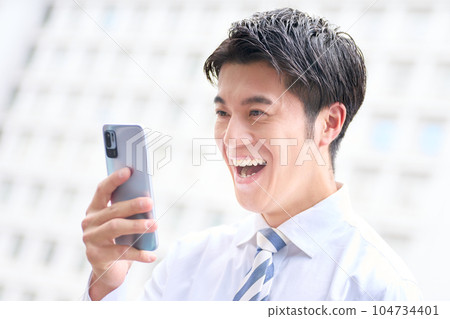 微笑著看著智能手機屏幕的商務人士 微笑著看著智能手機屏幕的商務人士 104734401