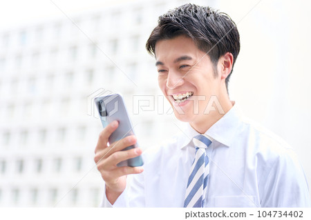 Business person laughing at the screen of the smartphone 104734402