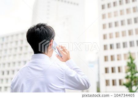 穿著襯衫的商務人士在戶外使用智能手機的後視圖 穿著襯衫的商務人士在戶外使用智能手機的後視圖 104734405