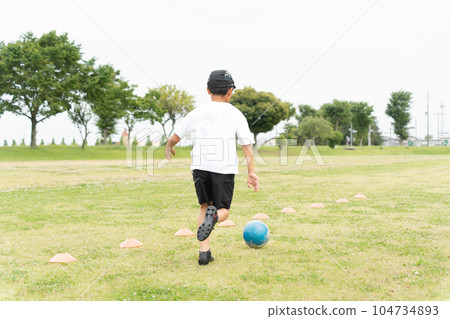 Asian kid playing soccer in the park Asian kid playing soccer in the park 104734893