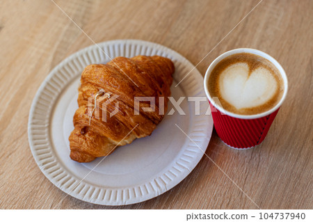 Cup of cappuccino with latte art and croissant on wooden table 104737940