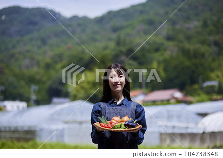 溫室前拿著新鮮採摘蔬菜的女農民 104738348