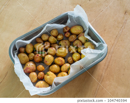Young whole potatoes with greens in baking tray 104740394