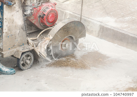Worker using diamond saw blade machine cutting concrete road at construction site Worker using diamond saw blade machine cutting concrete road at construction site 104740997