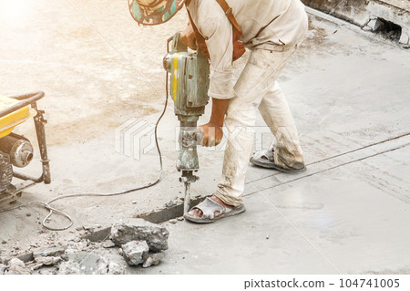 Construction worker using jackhammer drilling concrete surface Construction worker using jackhammer drilling concrete surface 104741005