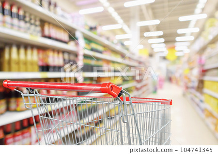 Empty shopping cart with abstract blur supermarket discount store aisle and product shelves interior defocused background Empty shopping cart with abstract blur supermarket discount store aisle and product shelves interior defocused background 104741345