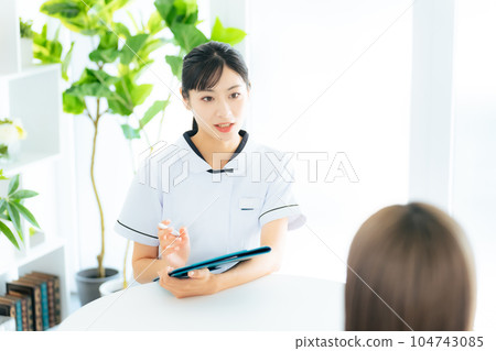 A female medical worker interviewing a patient A female medical worker interviewing a patient 104743085