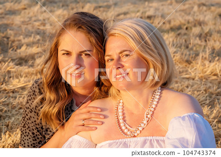 Happy lesbian couple sitting in a field. Same sex family, happy women. Smiling young lesbian couple. Happy lesbian couple sitting in a field. Same sex family, happy women. Smiling young lesbian couple. 104743374