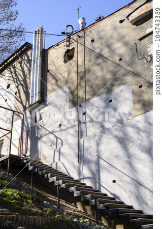 The wall of an industrial building with a staircase and nickel-plated shiny ventilation pipes 104743389