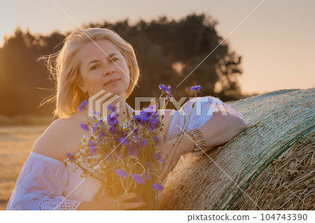 Portrait of attractive young woman in retro dress with a bouquet of wildflowers in countryside. Portrait of attractive young woman in retro dress with a bouquet of wildflowers in countryside. 104743390