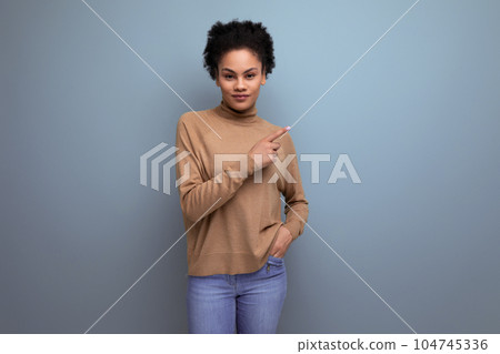 young pretty hispanic lady with afro curly hair in casual clothes posing against background with 104745336