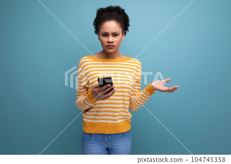 confused brunette brown-haired young woman with a mobile phone confused brunette brown-haired young woman with a mobile phone 104745358