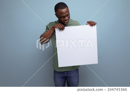 positive young smart american man in t-shirt showing white screen with mockup for information 104745360