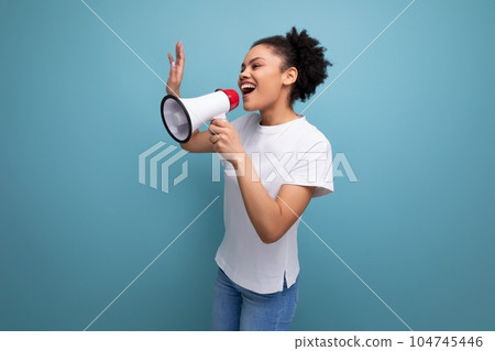young brunette latin woman in a white t-shirt uses a loudspeaker to announce important news on the 104745446