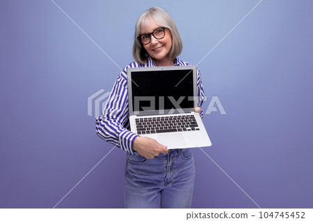 smiling 60s mature woman with gray hair with laptop mockup on bright studio background 104745452