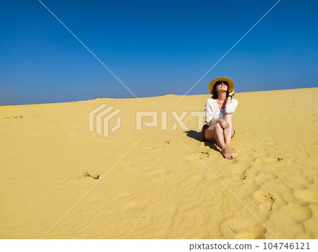 Young woman in white blouse and brown shorts walking in desert Young woman in white blouse and brown shorts walking in desert 104746121