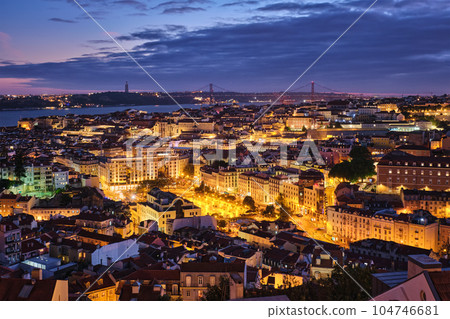 Night view of Lisbon famous view from Miradouro da Senhora do Monte tourist viewpoint of Alfama and Mauraria old city districts, 25th of April Bridge in the evening twilight. Lisbon, Portugal Night view of Lisbon famous view from Miradouro da Senhora do Monte tourist viewpoint of Alfama and Mauraria old city districts, 25th of April Bridge in the evening twilight. Lisbon, Portugal 104746681