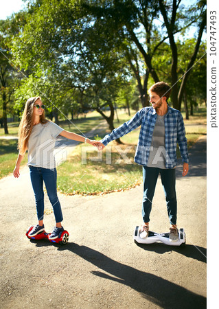 Young man and woman riding on the Hoverboard in the park. content technologies. a new movement. 104747493