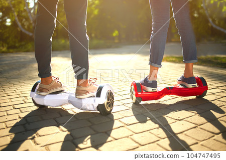 Young man and woman riding on the Hoverboard in the park. content technologies. a new movement. Young man and woman riding on the Hoverboard in the park. content technologies. a new movement. 104747495