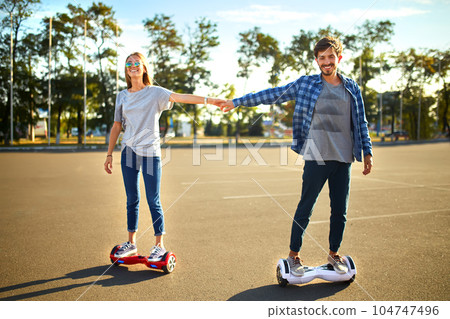 Young man and woman riding on the Hoverboard in the park. content technologies. a new movement. 104747496