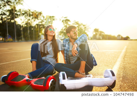 Young man and woman riding on the Hoverboard in the park. content technologies. a new movement. 104747498