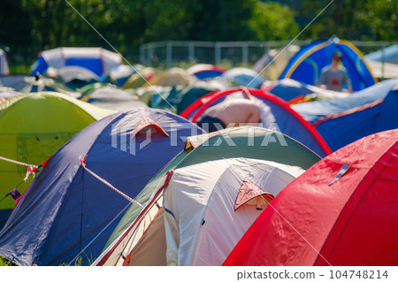Camping tents on ground in summer park during festival Camping tents on ground in summer park during festival 104748214