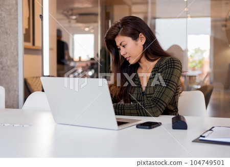 Focused woman working on laptop in office Focused woman working on laptop in office 104749501
