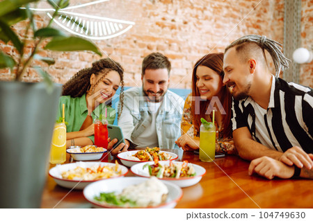 Happy friends having a great time in cafe. Young people sitting in a restorane having fun together 104749630