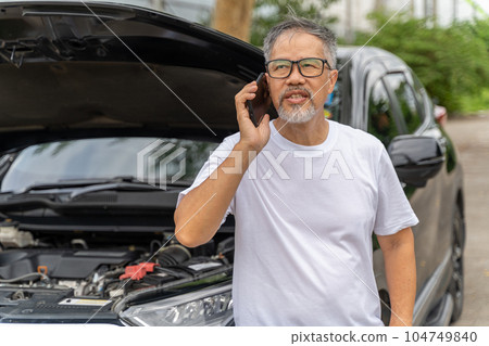 Middle age man with broken down car talking on his phone calling for help Middle age man with broken down car talking on his phone calling for help 104749840