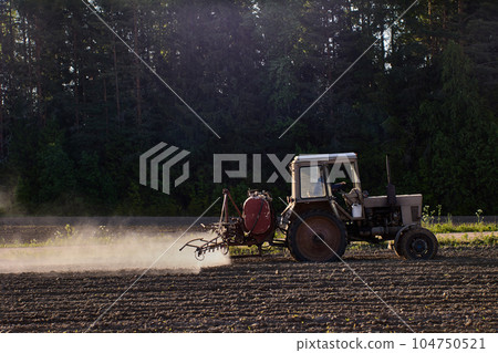 Applying herbicides to crops using sprayer on boom mounted on an agricultural tractor. Applying herbicides to crops using sprayer on boom mounted on an agricultural tractor. 104750521