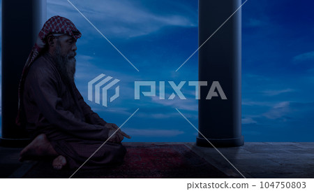 Muslim man with a beard wearing keffiyeh with agal in praying position (salat) on the prayer rug 104750803