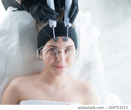 Young caucasian woman on microcurrent therapy procedure. Beautician's office. 104751013