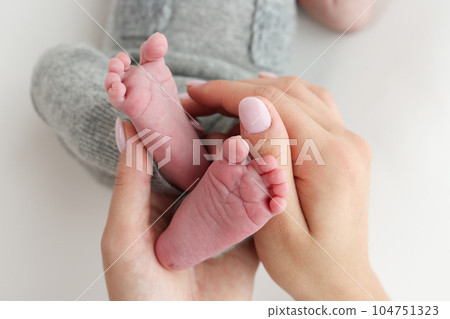 The palms of the father, the mother are holding the foot of the newborn baby on white background. Feet of the newborn on the palms of the parents. Photography of a child's toes, heels and feet. 104751323