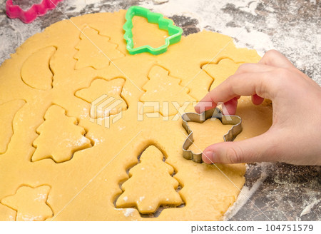 Kids hand with form of christmas cookies for children, making gingerbread in form of man. New year treat for Santa Claus cooking. Raw dough. Homemade bakery, xmas sweet, winter holidays concept 104751579