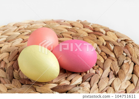 Easter colorful eggs in a basket on white wooden table. Burlap background. Happy Easter. Rustic, Eco concept. Dyed Eggs on a straw Napkin. Easter colorful eggs in a basket on white wooden table. Burlap background. Happy Easter. Rustic, Eco concept. Dyed Eggs on a straw Napkin. 104751611