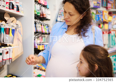 Mother and daughter choosing oil and watercolor paints in tubes, shopping in creative art store. School stationery shop Mother and daughter choosing oil and watercolor paints in tubes, shopping in creative art store. School stationery shop 104752565