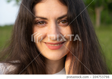 Portrait of a 35-year-old brunette woman looking at the camera smiling in nature. 104753798
