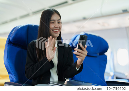 Asian business woman passenger sitting on business class luxury plane while working using smart phone mobile talking or video conference and travel concept. Asian business woman passenger sitting on business class luxury plane while working using smart phone mobile talking or video conference and travel concept. 104754602