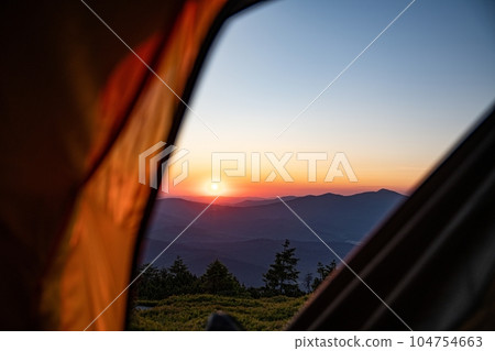 Sunrise seen from a tent in the mountains. The sun rises over Babia Gora - the highest mountain in the Zywiecki Beskids Sunrise seen from a tent in the mountains. The sun rises over Babia Gora - the highest mountain in the Zywiecki Beskids 104754663
