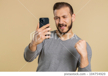 Happy excited young winner man use smartphone say wow yes found out great big win good news lottery Happy excited young winner man use smartphone say wow yes found out great big win good news lottery 104754920
