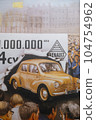 19 April 2023 Paris, France. Photo of a poster celebrating production of one million Renault 4cv showing a yellow car breaking through a paper banner while crowds of people cheer. Factory workers 104754962