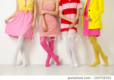 Women wearing colorful tights near white wall, closeup Women wearing colorful tights near white wall, closeup 104756301