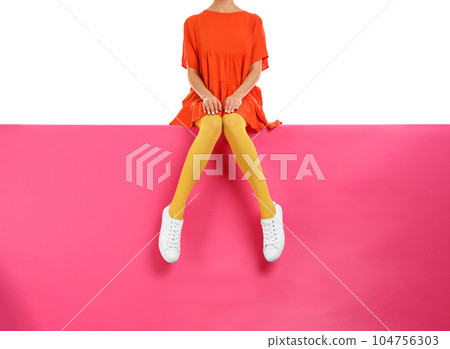 Woman wearing yellow tights and stylish shoes sitting on color background, closeup Woman wearing yellow tights and stylish shoes sitting on color background, closeup 104756303